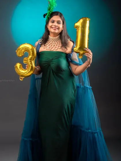 A smiling portrait in the peacock gown, ready for a birthday celebration. The statement necklace completes this glamorous party look.