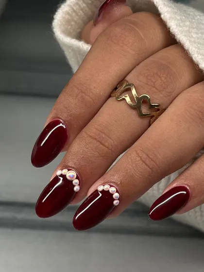 A classic deep red manicure gets a sophisticated upgrade with a beautiful pearl accent along the cuticle.