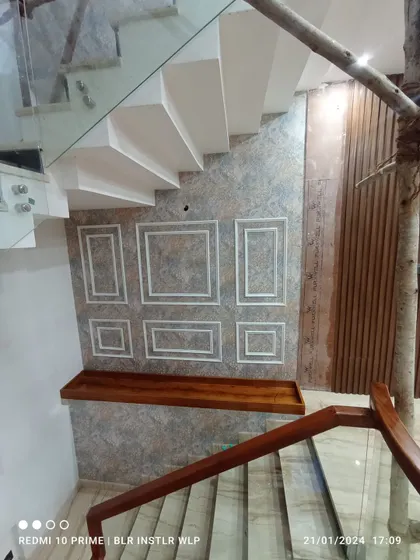 A textured wallpaper installed on a staircase wall, with moulding applied on top to create a paneled effect.