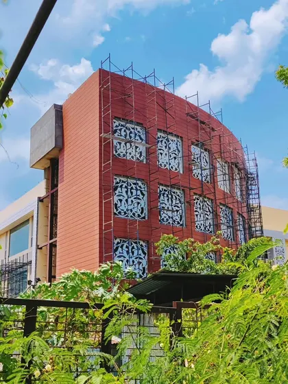 The clubhouse for Arihant Aspire under construction in Panvel. The photo shows the curved terracotta-colored facade and the intricate jali work being installed.