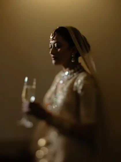 A soft-focus, dreamy shot of the bride holding a glass of champagne, creating an intimate and celebratory mood.