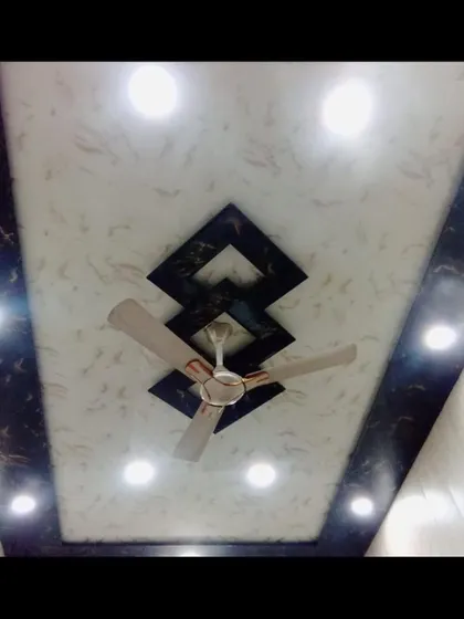 Marble finish PVC panels ke saath dark border ka yeh design bohot popular hai. Yeh aapke fan ke aas-paas ek accha frame banata hai.