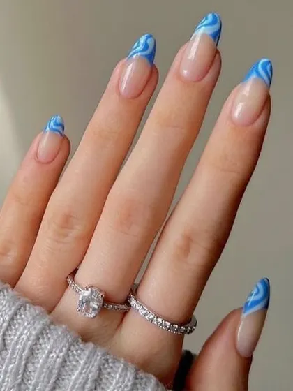 Make waves with this stunning blue swirl French manicure. The design features a dynamic, wavy pattern of two-toned blue on the tips of long almond nails for a fresh, ocean-inspired look.