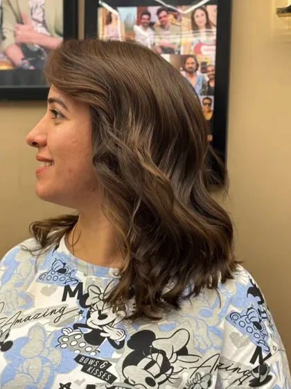 A side view of a client's new cut and color. The soft waves and subtle highlights create a chic and sophisticated style.