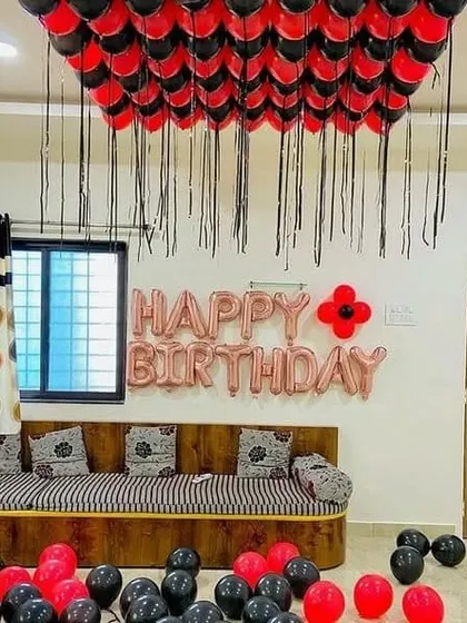 A red and black themed room decoration with balloons covering the ceiling.