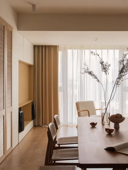 A minimalist dining space with a simple wooden table and chairs featuring woven cane seats. The design emphasizes natural materials and clean lines for a light and airy feel.