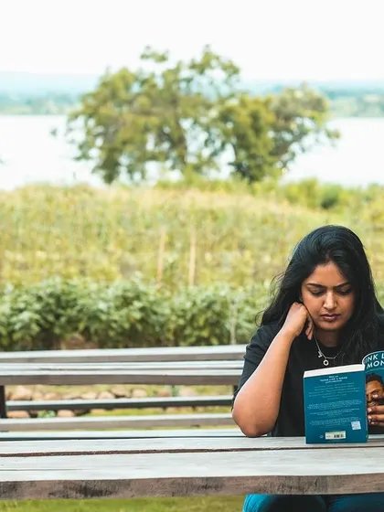 Our campsite offers plenty of quiet spots for relaxation. Here, a guest enjoys a book at a picnic table with a peaceful view of the lake in the background.