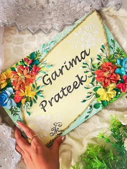 Holding the "Garima & Prateek" nameplate to show its scale and how the colors shine in natural light.