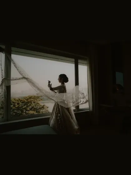 A colored silhouette of the bride against the window, with the city and trees visible outside.