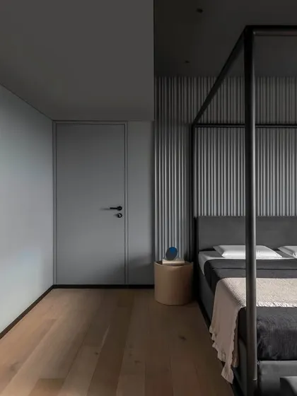 Another view of the master bedroom in 'A Hint of Azul', showing the irregular fluted paneling and light oak wooden floor. The four-poster bed acts as a strong geometric counterpoint to the soft curves in the ceiling.