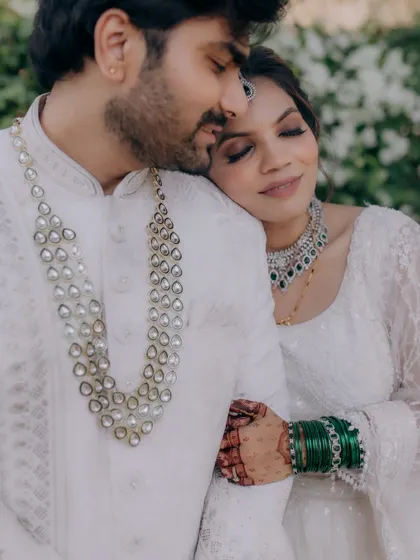 A tender moment between the couple. The bride's elegant makeup complements her modern white lehenga and the groom's classic attire.