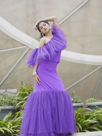 Posed in a garden, the vibrant purple of this gown stands out beautifully against the green foliage.