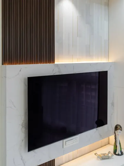 This TV wall is a beautiful example of texture play, combining a marble-finish panel with dark fluted wood and soft backlighting for a dramatic and modern effect.