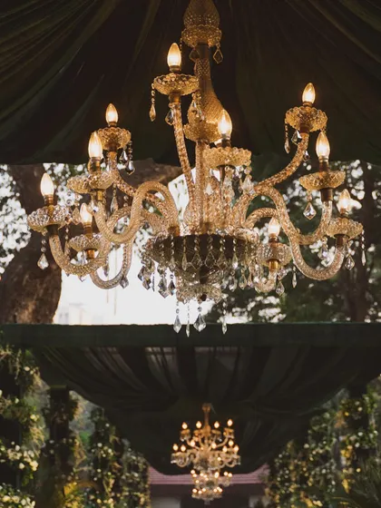 Classic elegance for an evening affair. A stunning crystal chandelier hangs beneath deep green draped fabric, creating a sense of timeless romance and sophistication for an intimate wedding celebration.