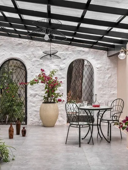 The spacious patio was designed to feel like a Mediterranean courtyard. With its rough-textured walls, arched niches, and plentiful greenery, it’s a versatile space for relaxing or entertaining.
