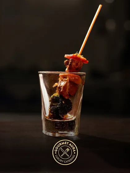 A single skewer with grilled chicken and broccoli presented in a shot glass. A stylish and convenient way to serve delicious appetizers.