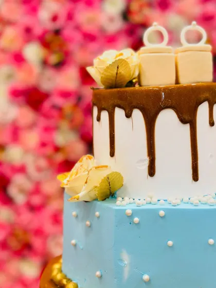 A close-up of the engagement ring toppers on the three-tiered cake, showing the fine details.