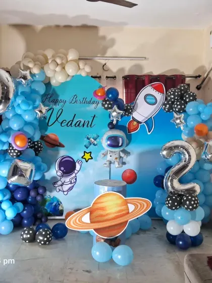 A detailed view of the space-themed birthday decoration for Vedant's second birthday. The setup includes a custom backdrop, astronaut and planet cutouts, and a balloon galaxy.