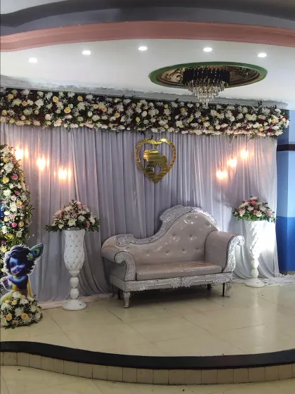 The stage setup for the Krishna-themed baby shower, showing the elegant chaise lounge and floral vases.
