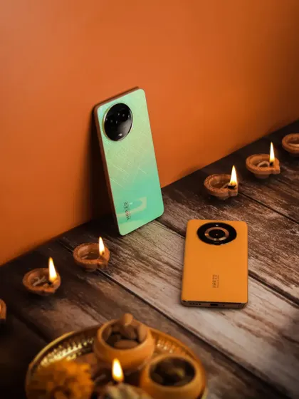A festive product shot with two Narzo phones, diyas, and a traditional thali, set against a warm, textured background.