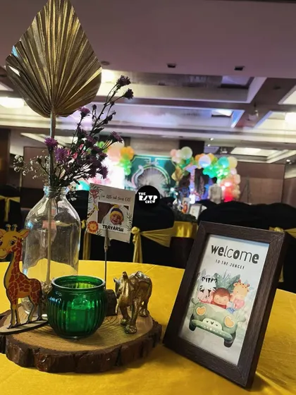 A jungle-themed table centerpiece with a 'Welcome to the Jungle' sign, a wooden giraffe, and a golden elephant.