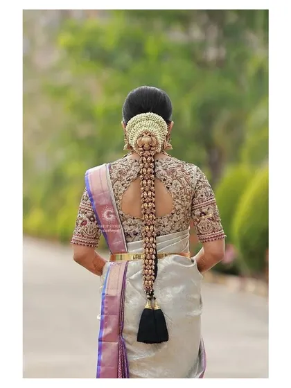 A detailed look at Vishnu Priya's bridal hairstyle from the back. The traditional braid is adorned with a beautiful hair accessory, completing her classic South Indian bridal look.