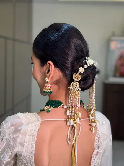A close up of this intricate bridal bun, adorned with a stunning traditional hair accessory that cascades down her back.