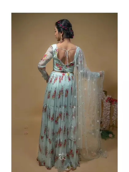 The back view of the baby blue floral lehenga, showing the elegant tie-back detail on the blouse and the graceful flow of the tiered skirt and dupatta.