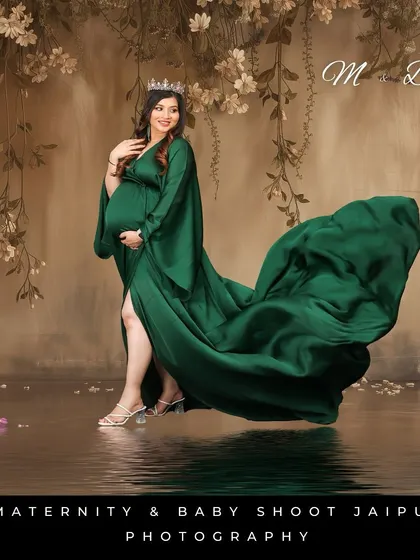 A glamorous studio shot with a water reflection effect. The woman's emerald green gown flows beautifully against a painterly, floral backdrop, creating a high-art portrait.