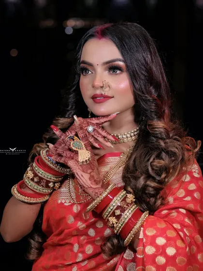A close-up shot focusing on the model's hands, showcasing her intricate henna design and traditional red and gold bangles.