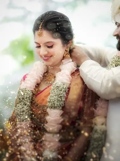 A dreamy, soft-focus shot of a wedding ritual. The floating particles, likely rice or turmeric, add a magical quality to this sacred moment.