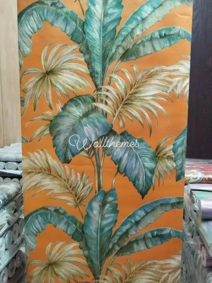 This vibrant tropical leaf wallpaper, shown here unrolled, is perfect for creating a bold and lively accent wall. The bright orange background and lush green foliage bring a touch of nature indoors.