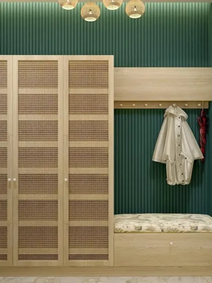This entryway in Mr. Aniketh's home is a perfect example of functional Indian Bohemian design. It features a wardrobe with cane shutters, a comfortable seating bench, and coat hooks against a rich green fluted wall.