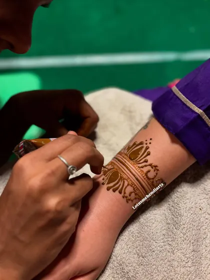 Creating a perfectly symmetrical and detailed wrist cuff is a skill we practice extensively. This close up shows the application of a lotus themed band, a versatile element in many mehendi designs.