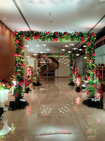 A magnificent square floral arch made of red roses, with delicate illuminated birds hanging from the center. This design creates a stunning frame for the venue's entrance.