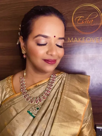 A subtle and graceful look for a wedding guest. The makeup features soft, neutral eyeshadow and a muted red lip, which looks beautiful with her golden silk saree and traditional jewelry.