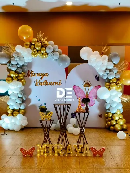 A chic and modern butterfly-themed birthday for Miraya. The double-arched backdrop is decorated with a stylish grey, white, and gold balloon garland.