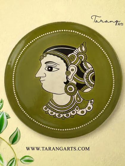 This hand-painted wooden plate features a portrait in a classic Indian art style. The olive green background and delicate white details create an elegant and understated piece of wall decor.
