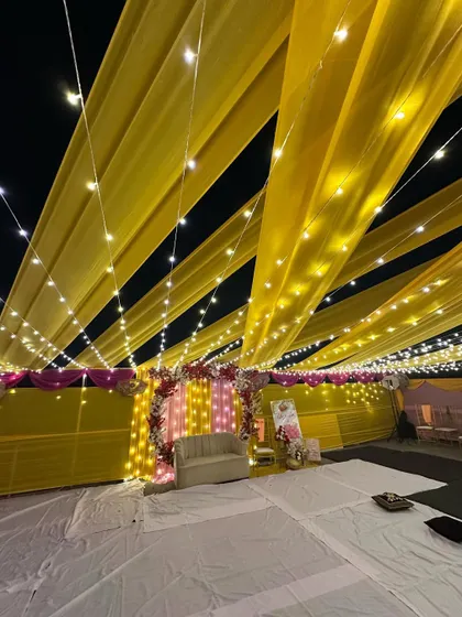 A wide shot of the terrace transformed for a night event. The entire space is covered with yellow drapes and a web of fairy lights, creating a magical canopy.