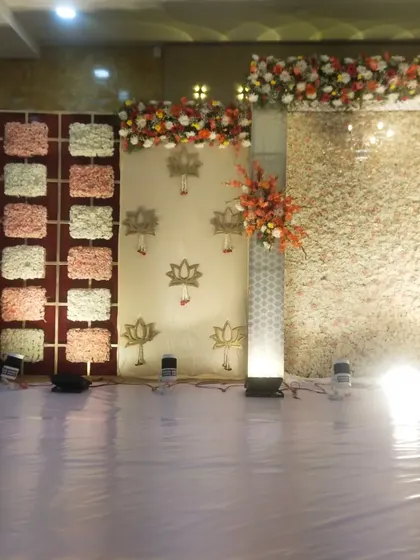 A side angle of the reception decor, showing the different panels used in the backdrop. This includes the main flower wall, a section with lotus motifs, and a checkered floral panel.