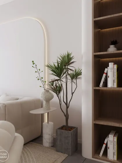 A detail shot showing how we blend natural and refined elements. A potted plant in a concrete planter stands next to a side table with a marble base, demonstrating our love for mixing materials and textures. The arched wall with cove lighting adds a soft architectural detail.
