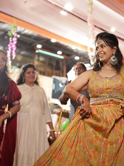 A happy bride dancing at her sangeet, her henna-stained hands part of her joyful expression.