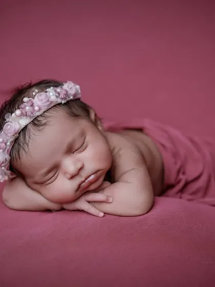 A sleeping beauty in pink. This simple, classic pose on a soft magenta background highlights the baby's delicate features.