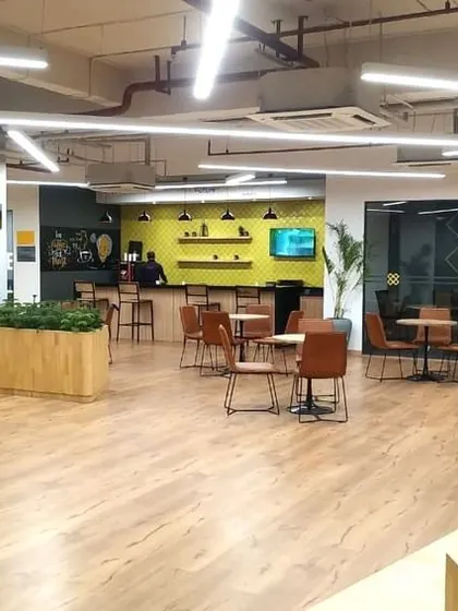 A view of the spacious and open layout of the VentureX office. The use of wood-look flooring and strategically placed planters creates a warm and natural flow through the space.
