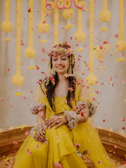A serene portrait of the bride amidst a shower of petals, her eyes closed and a gentle smile on her face, enjoying the moment.