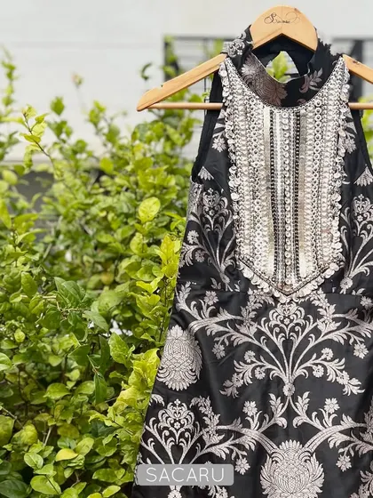 A statement piece for any festive occasion. This black brocade halter top is defined by its heavily hand embroidered neckline, featuring a dense pattern of silver metal sequins and beads.