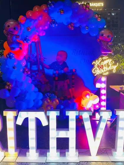 A full view of the Cocomelon themed first birthday party for Rithvik, showing the large light-up letters and balloon backdrop.