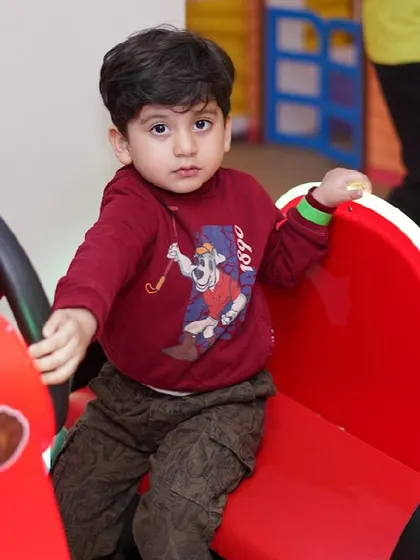 A toddler enjoys a ride in one of our small toy cars.