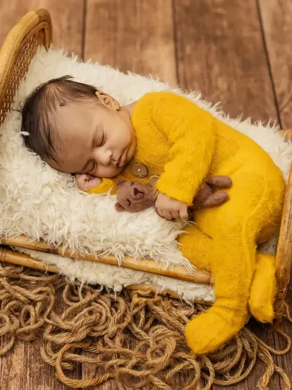 This little one looks so peaceful sleeping on the miniature bed, a perfect setup for a classic newborn portrait.