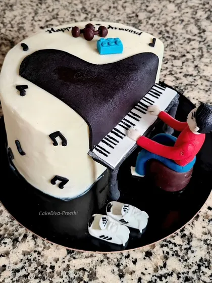 This cake was designed for a piano lover. It features a grand piano shape with a fondant figure playing it, along with other personal touches like fondant dumbbells and Adidas shoes.